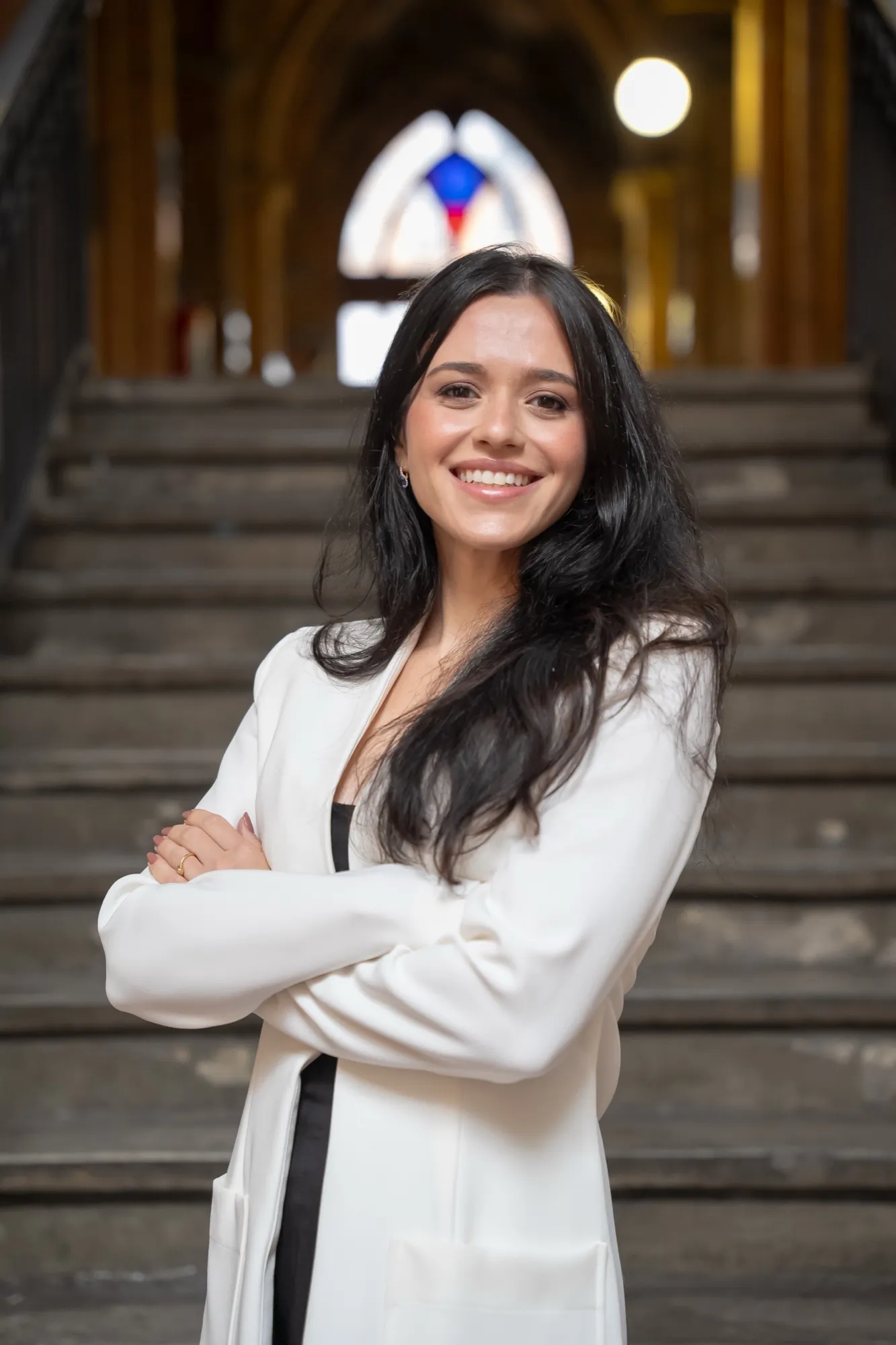 Dra. Letícia Gaspar de braços cruzados, sorrindo, de blazer branco